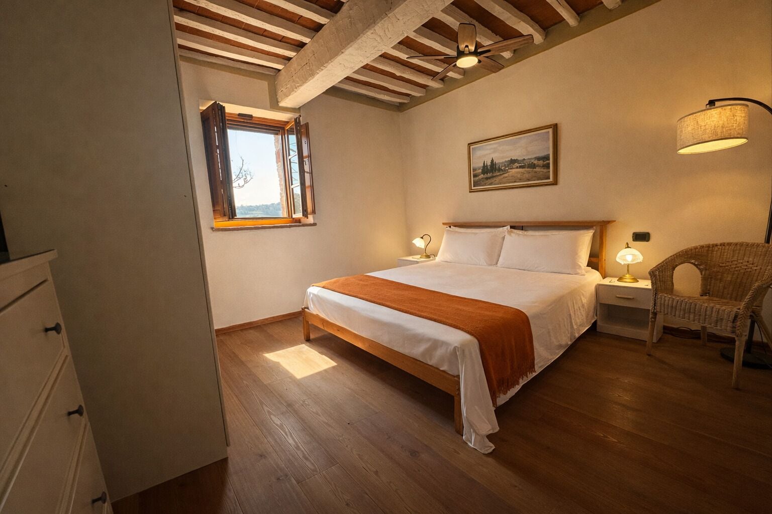 Un dormitorio con techo de madera, una cama con ropa de cama blanca, una ventana, una silla y una mesita de noche con lámparas.