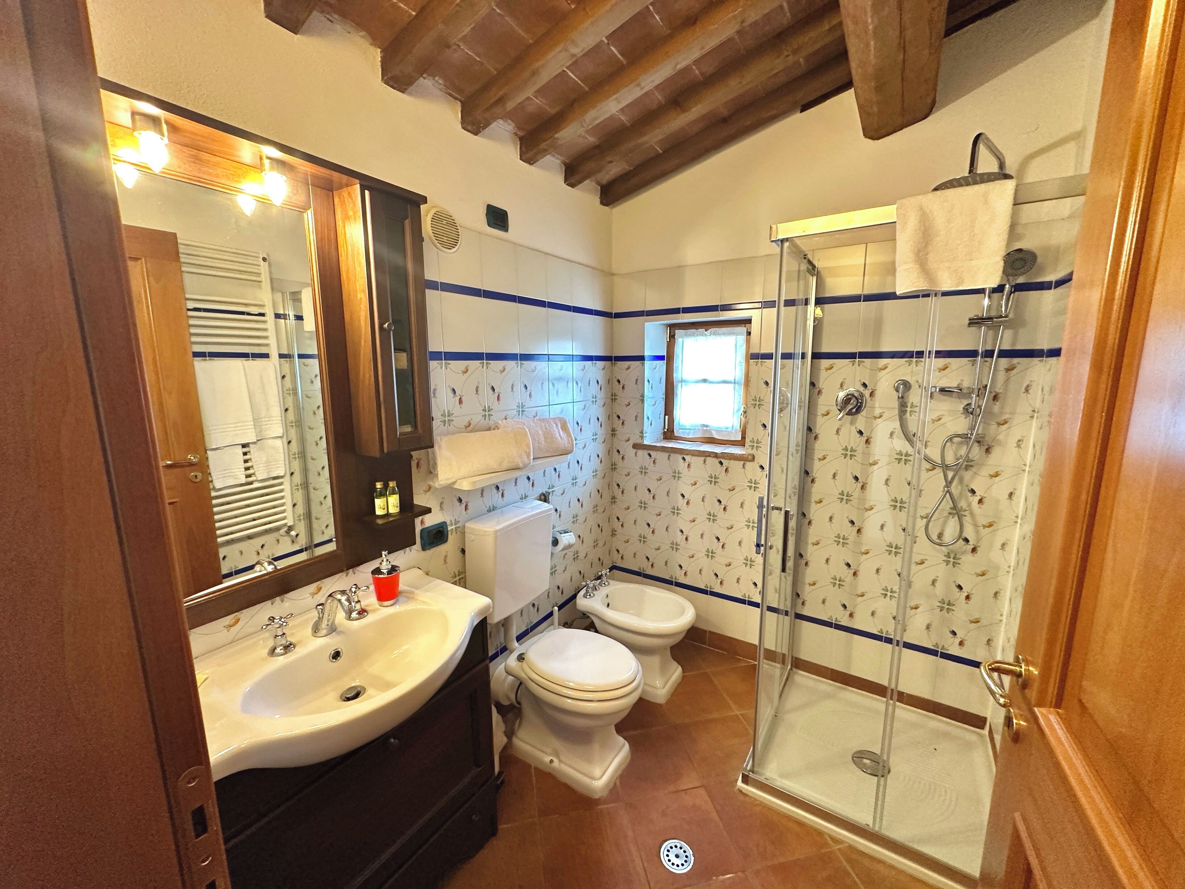 Ein Badezimmer mit Waschbecken, zwei Toiletten, einer Dusche und einem Fenster.