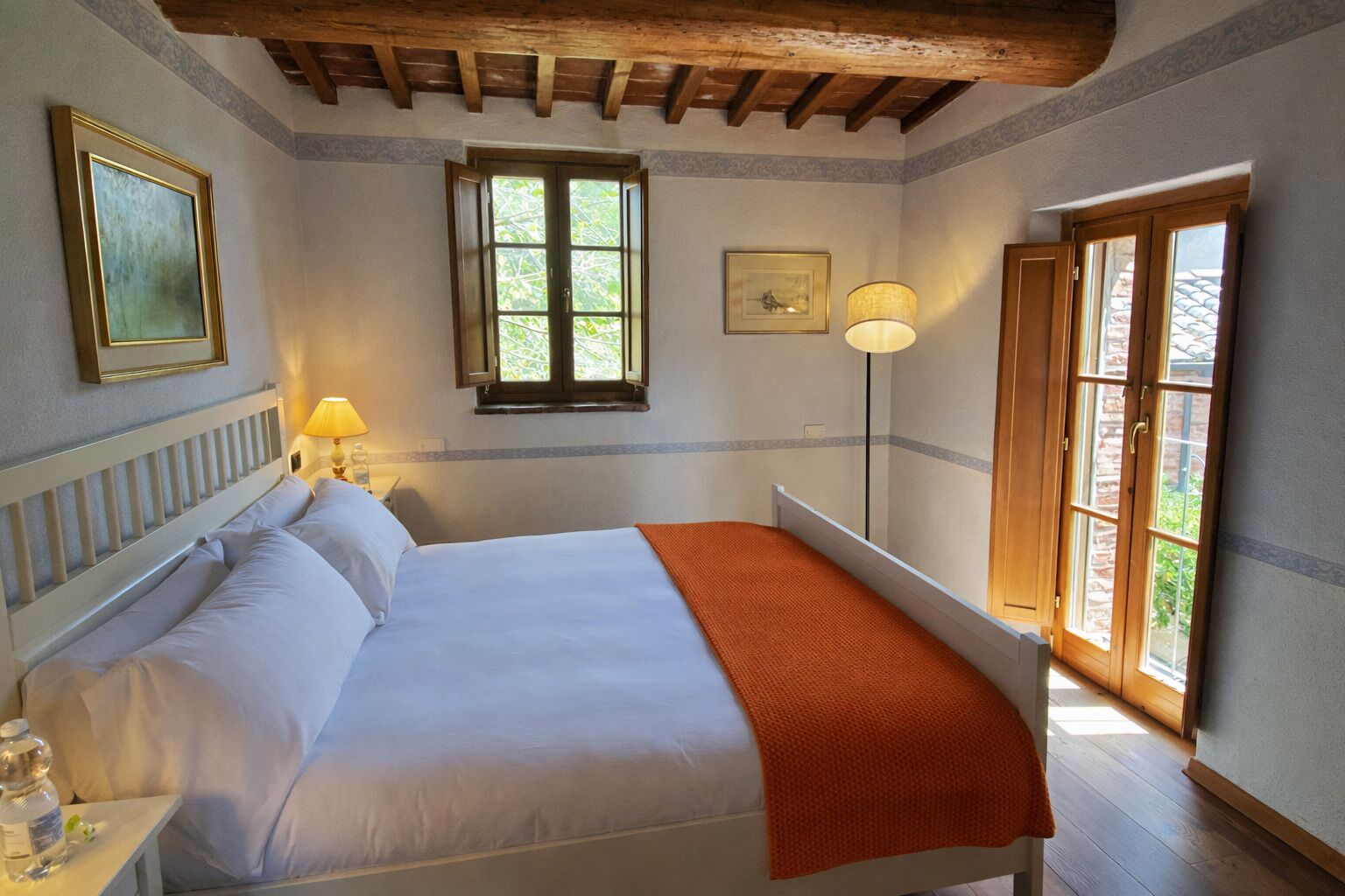 Una camera da letto con un letto, un comodino, una lampada, una finestra e una porta.