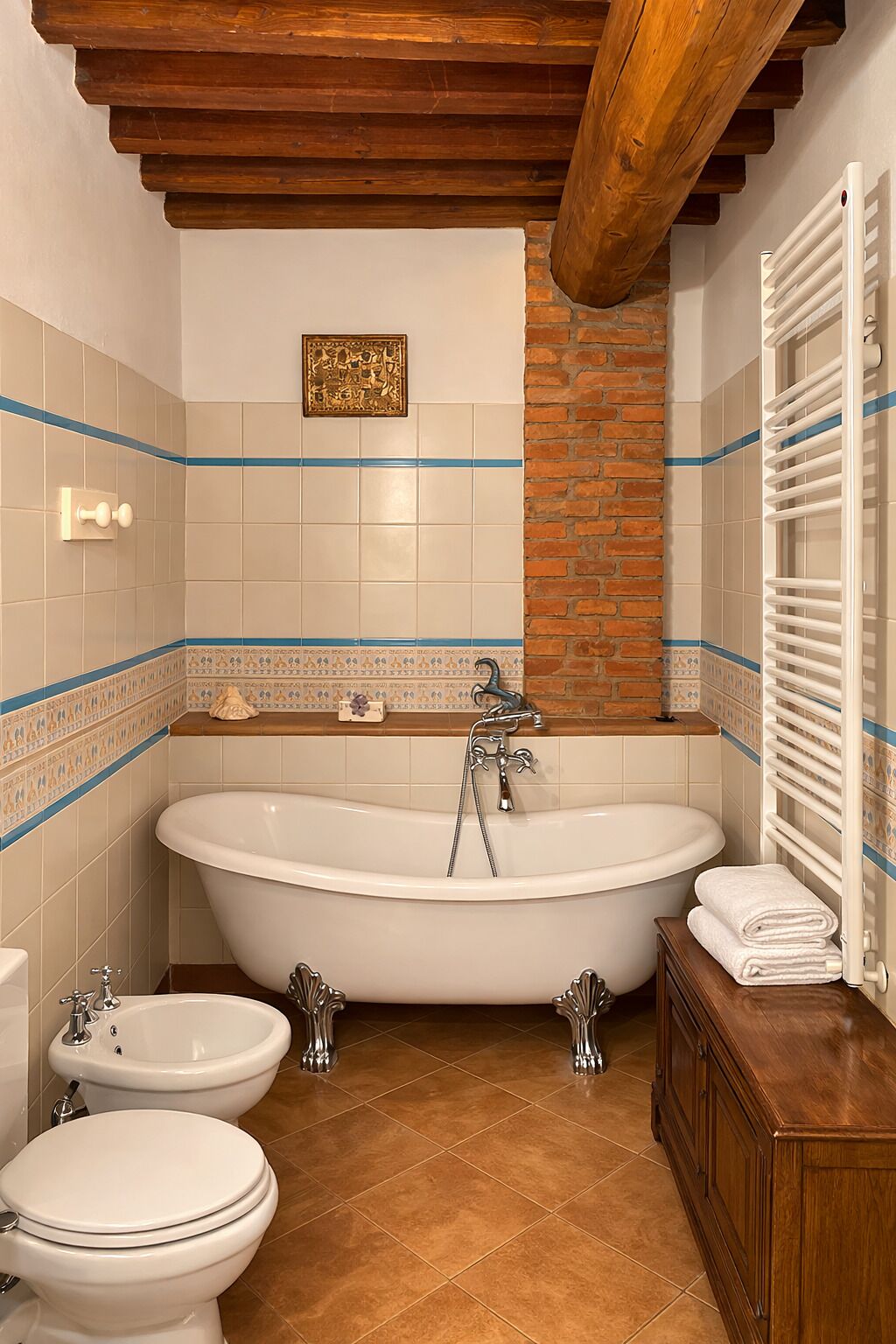 Et badeværelse med et fristående badekar, to håndvaske, et toilet og en radiator.