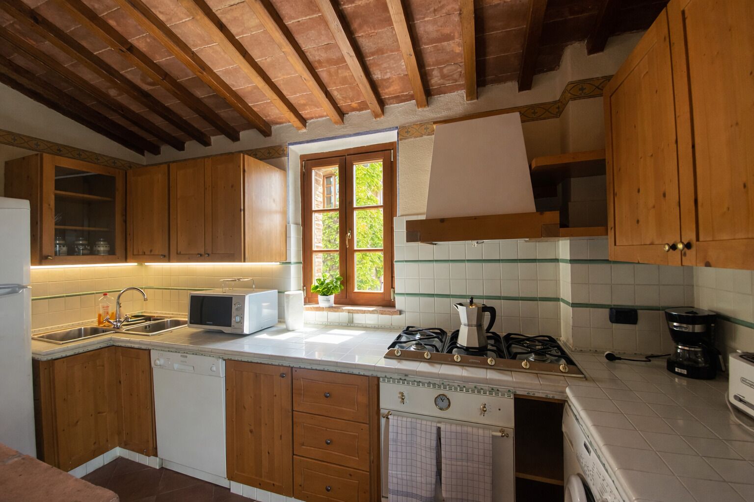 A kitchen with wooden cabinets, a window, a stove, and a dishwasher.