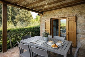 A covered patio with a table set for two, featuring a book, coffee cups, and croissants. - Agriturismo Borgo Sette Tigli (Montepulciano)