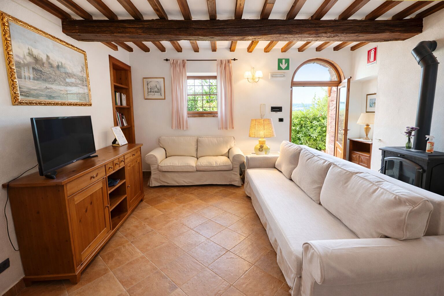 A living room with a television, wooden cabinet, two sofas, a lamp, and a fireplace.