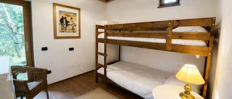 A bunk bed room with a small table and chair, a lamp, and a framed picture on the wall.