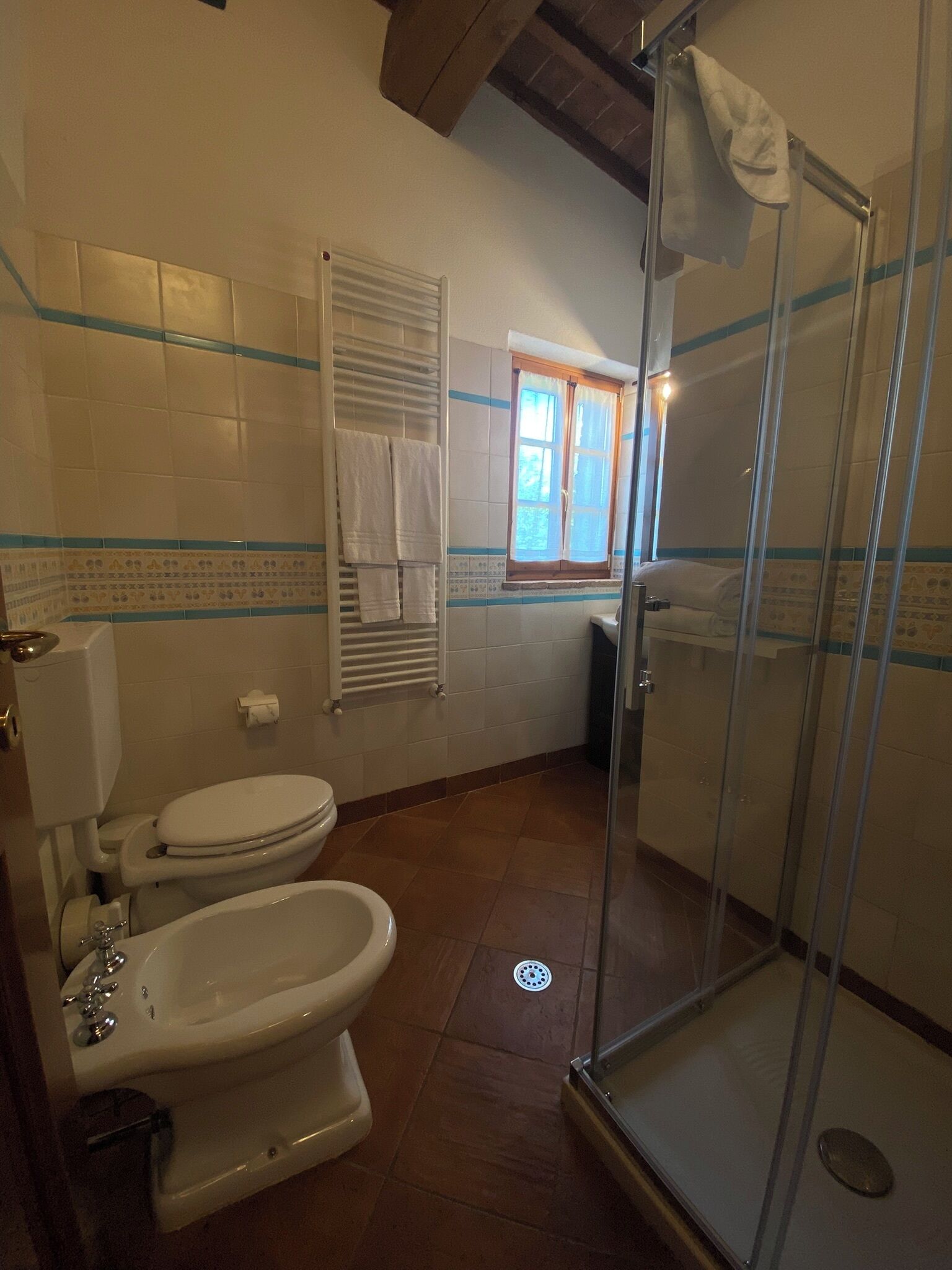 Een badkamer met toilet, bidet en een douche met glazen wanden.