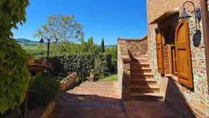 A stone building with a wooden door and a staircase leading to a covered area. - Agriturismo Borgo Sette Tigli (Montepulciano)