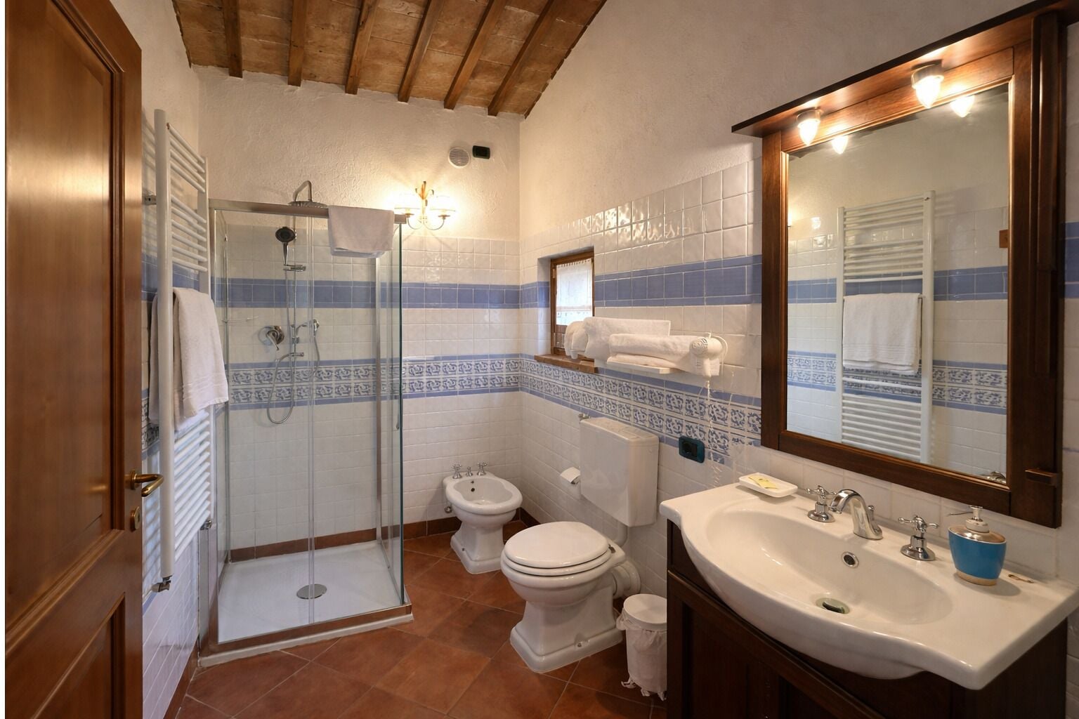 A bathroom with a shower, toilet, bidet, and sink.