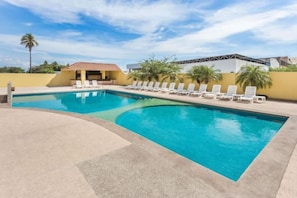 Une piscine avec des chaises longues et un petit bâtiment en arrière-plan.