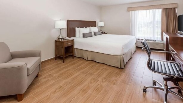 A hotel room with a bed, a desk, a chair, a TV, and a window. - Baymont by Wyndham Lazaro Cardenas (Lazaro Cardenas)