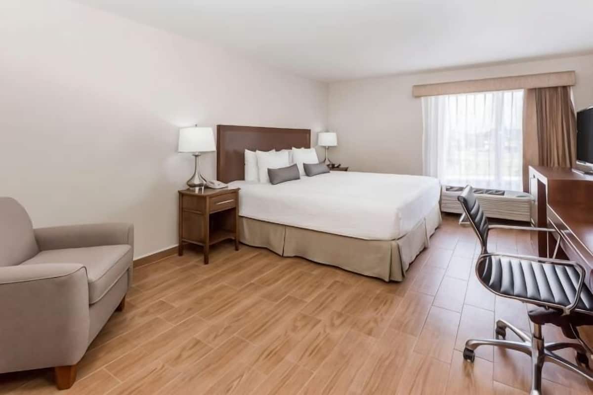 Ein Hotelzimmer mit Bett, Schreibtisch, Stuhl, Fernseher und Fenster.