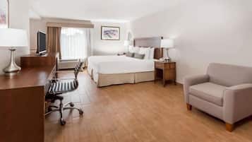 A hotel room with a bed, a desk, a chair, a sofa, and a window with curtains.