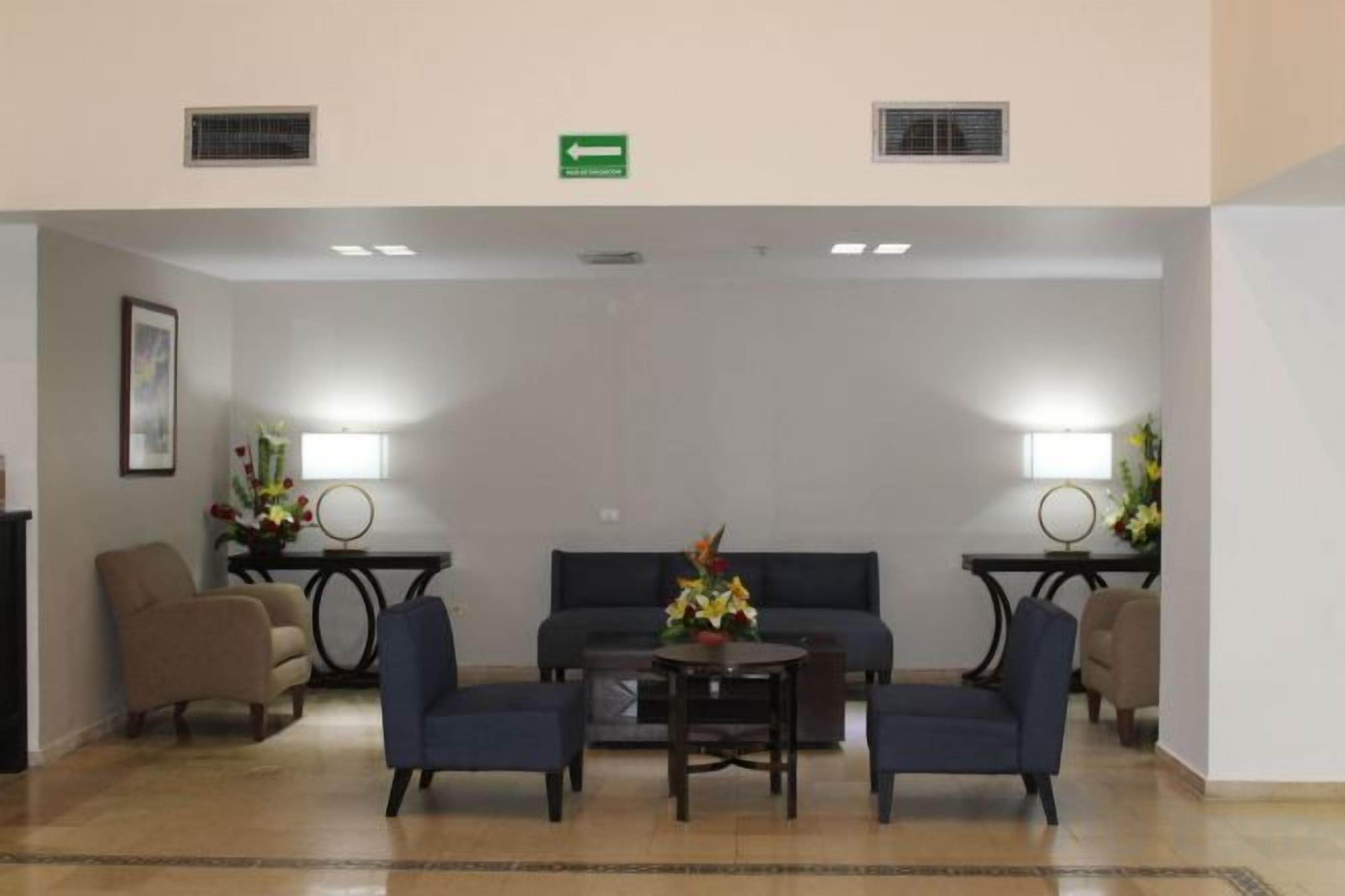 A lobby with a sofa, chairs, a table, and lamps.