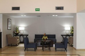 A lobby with a sofa, chairs, a table, and lamps.
