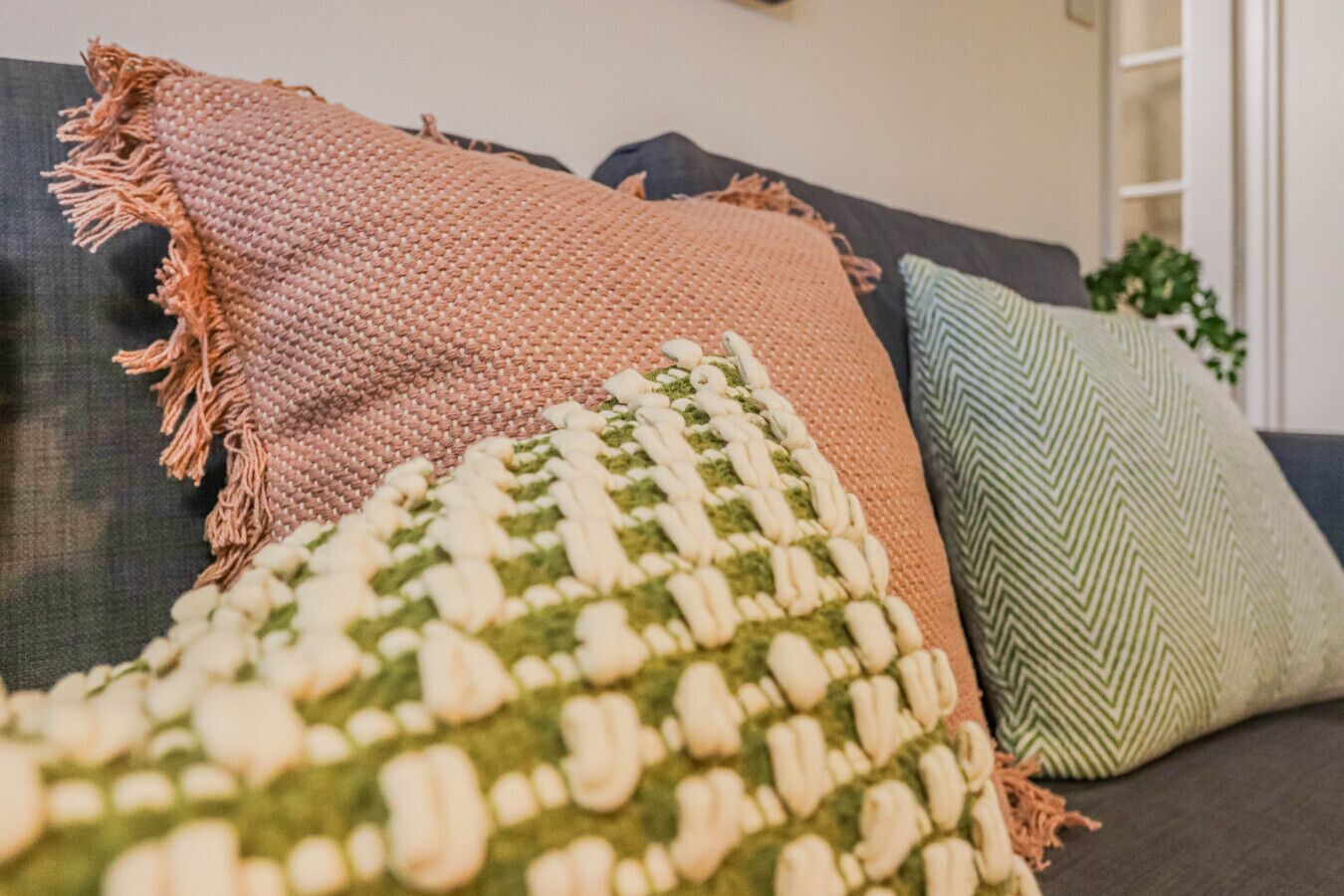 A sofa with three pillows in different patterns and colors.
