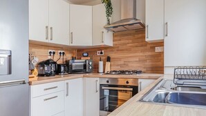 A modern kitchen with white cabinets, a wooden countertop, a built-in oven, a gas stove, and a sink. - Samantha Suite | City 2BR Bungalow Free Parking Garden & WIFI (Cardiff)