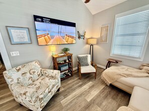 A living room with a TV, a sofa, a chair, a lamp, and a window with blinds.