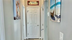 Um corredor com um tapete estampado, uma porta com a placa 'Weekend Getaway' e duas pinturas nas paredes.