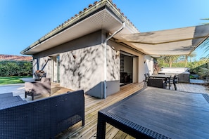 Een terras met buitenmeubilair, een barbecue en een overdekte zithoek.