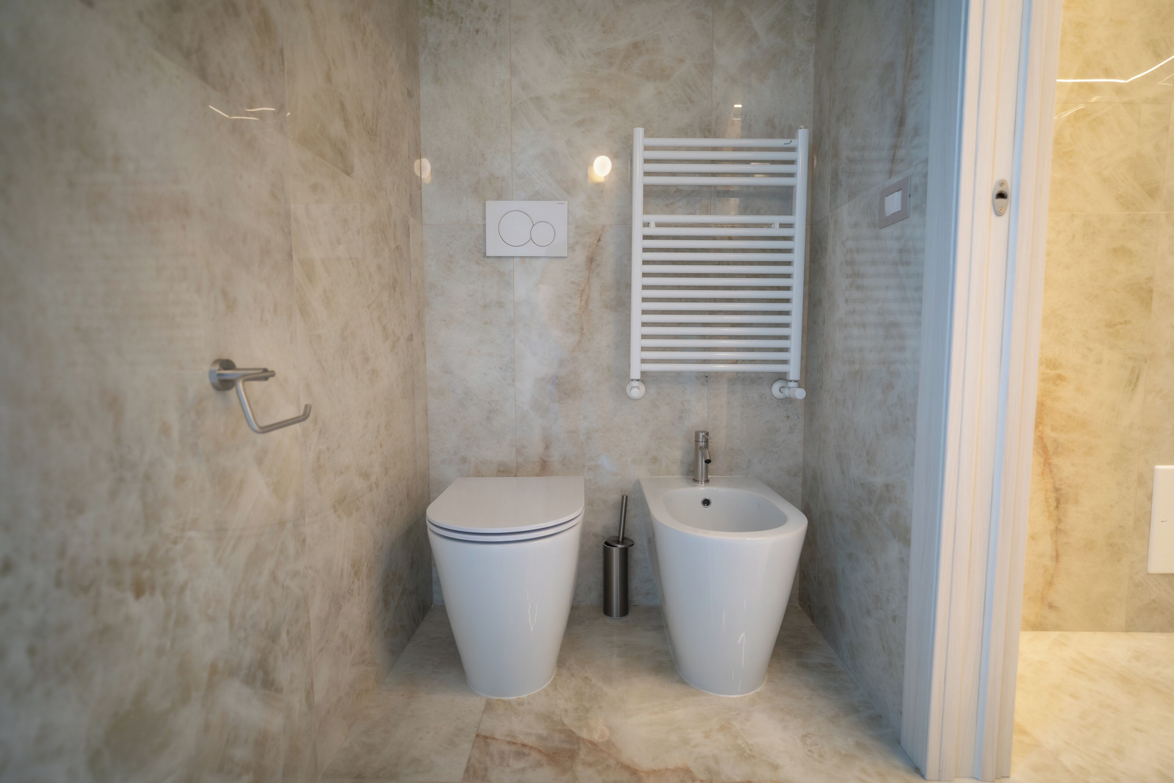Ein Badezimmer mit Toilette, Bidet und Handtuchhalter.