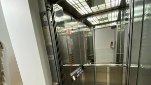 Un ascensor con pantalla digital, interior metálico y puerta de cristal.