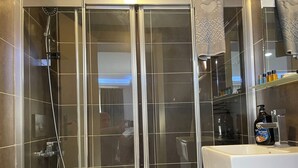 Un baño moderno con ducha de vidrio, un lavabo blanco y un espejo encima.