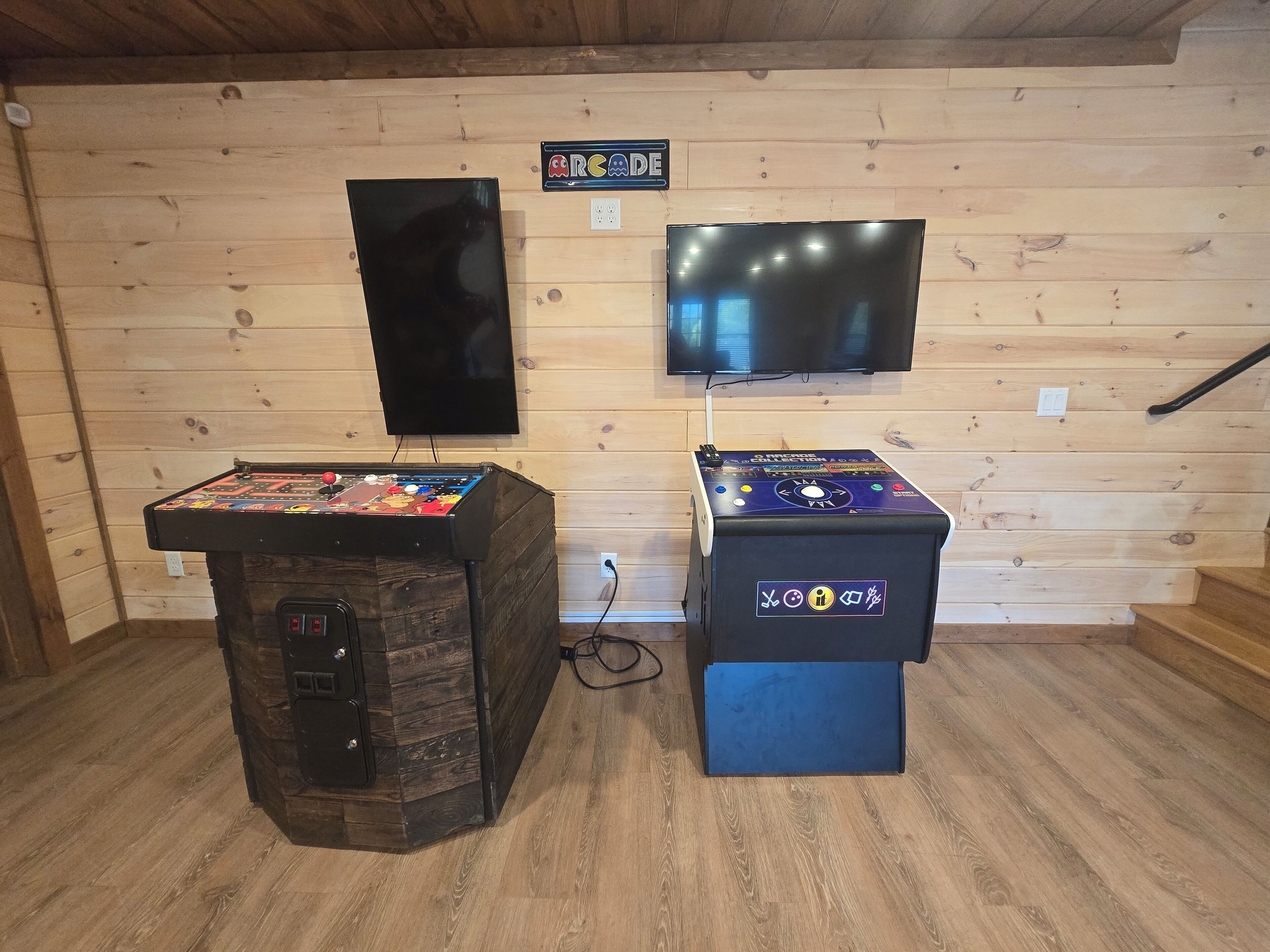 Zwei Spielautomaten in einem Raum mit Holzwänden und einem darüber angebrachten Fernseher.