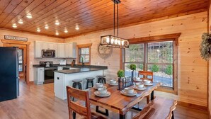 A spacious kitchen with wooden cabinets, a central island with stools, and a dining table set for four.