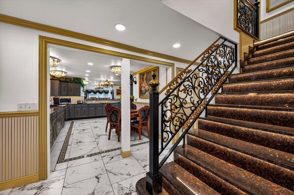 A grand staircase with a black metal railing and marble steps.