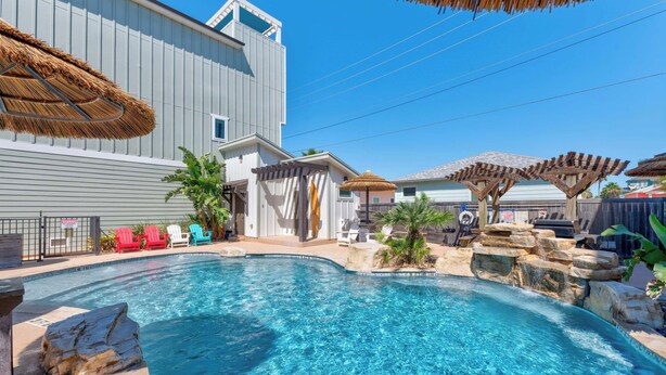 A swimming pool with clear blue water, surrounded by lounge chairs and a pergola. - Spacious TownHouse ~ Walk to Beach ~ Resort Pool (Port Aransas)