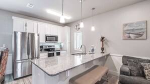 A modern kitchen with white cabinets, stainless steel appliances, and a granite countertop. - Spacious TownHouse ~ Walk to Beach ~ Resort Pool (Port Aransas)
