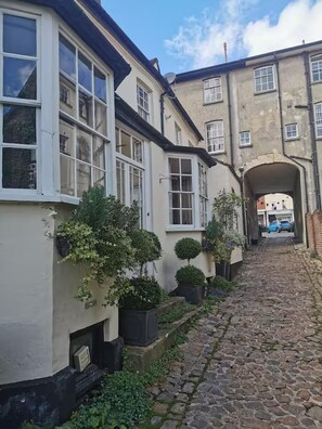 A narrow cobblestone street flanked by buildings with white-framed windows and a brick archway. - 17th Century Coach House - Pet & Family Friendly (Marlborough)