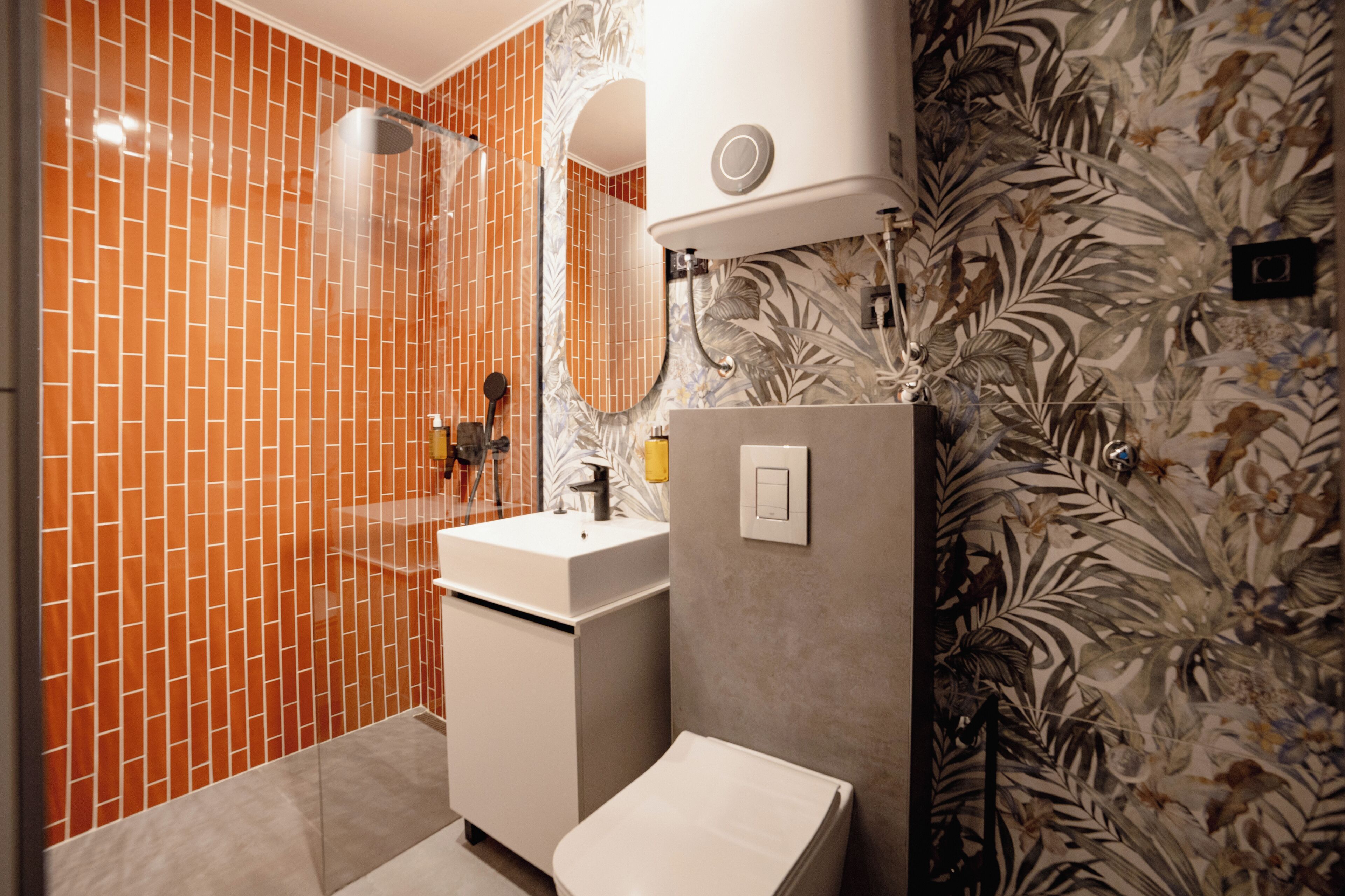 A bathroom with a tiled shower, a sink, and a toilet.