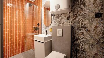 A bathroom with a tiled shower, a sink, and a toilet.