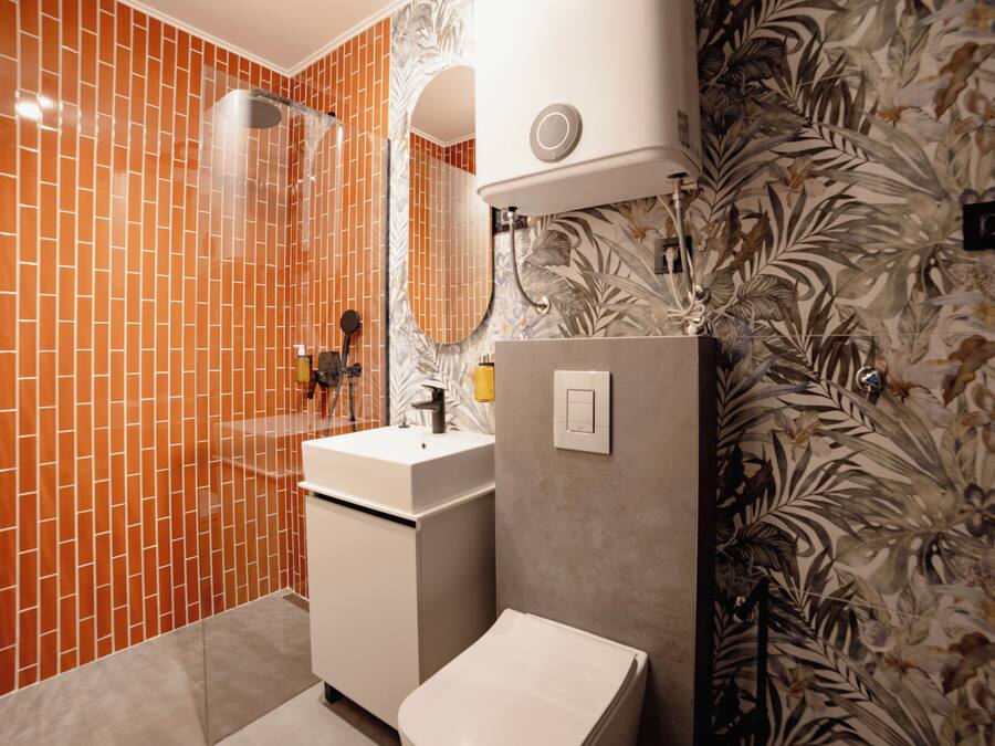 A bathroom with a tiled shower, a sink, and a toilet.