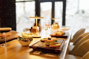 Une table à manger dressée avec une variété de plats et de boissons, notamment un saladier rempli de salade, un verre de vin et plusieurs assiettes de nourriture.