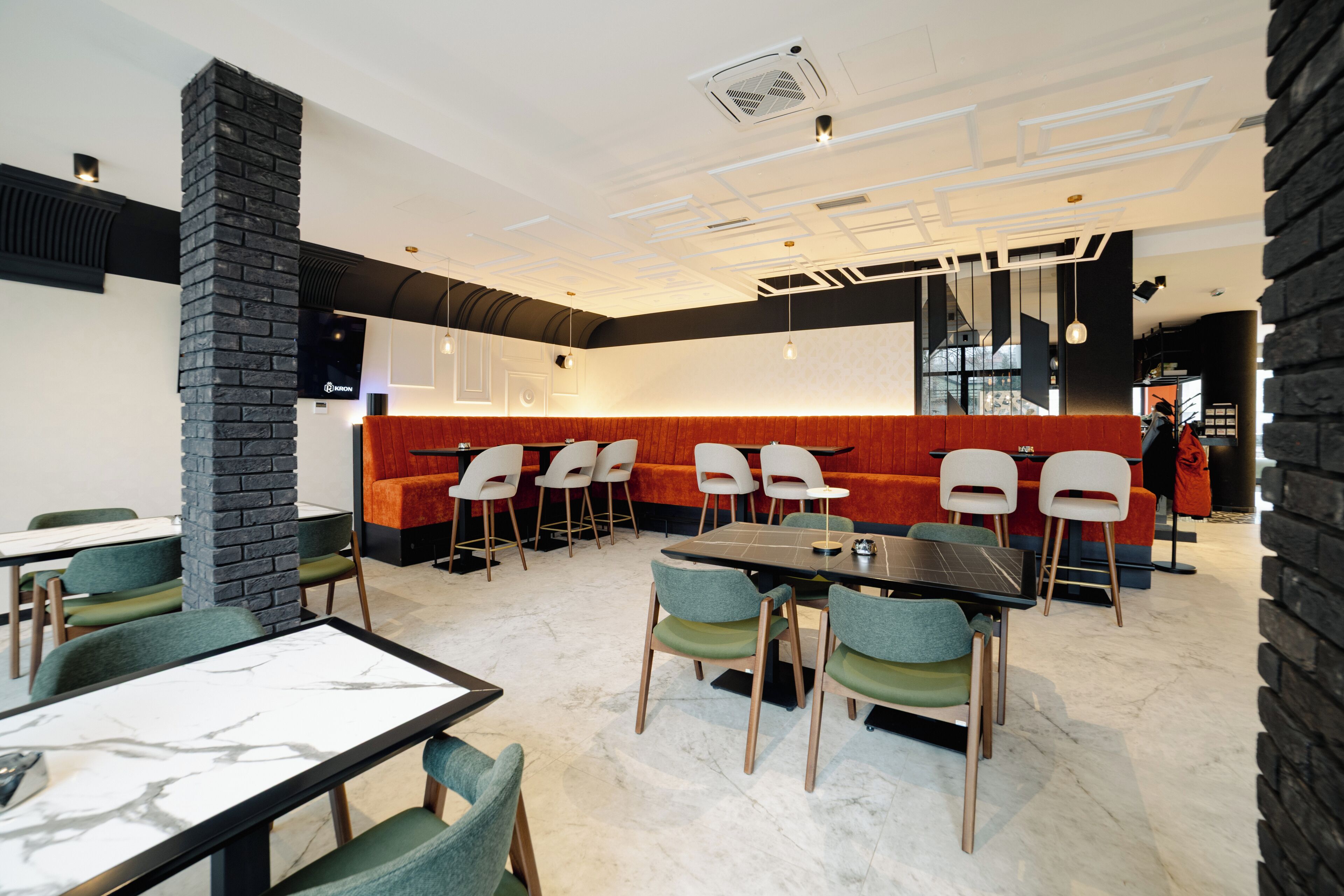 A modern restaurant with a mix of seating options, including booths and tables, and a distinctive black brick column.