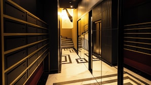 A hallway with a geometric patterned floor, a staircase, and a row of lockers on the left. - Kron (Novi Sad)