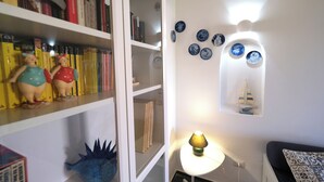 Quarto com estante, pratos decorativos e abajur.