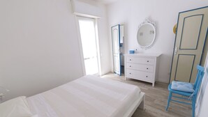 Quarto com cama, penteadeira, espelho e cadeira.
