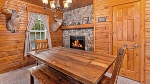 A wooden cabin interior with a stone fireplace, wooden walls, and deer antlers mounted on the wall.