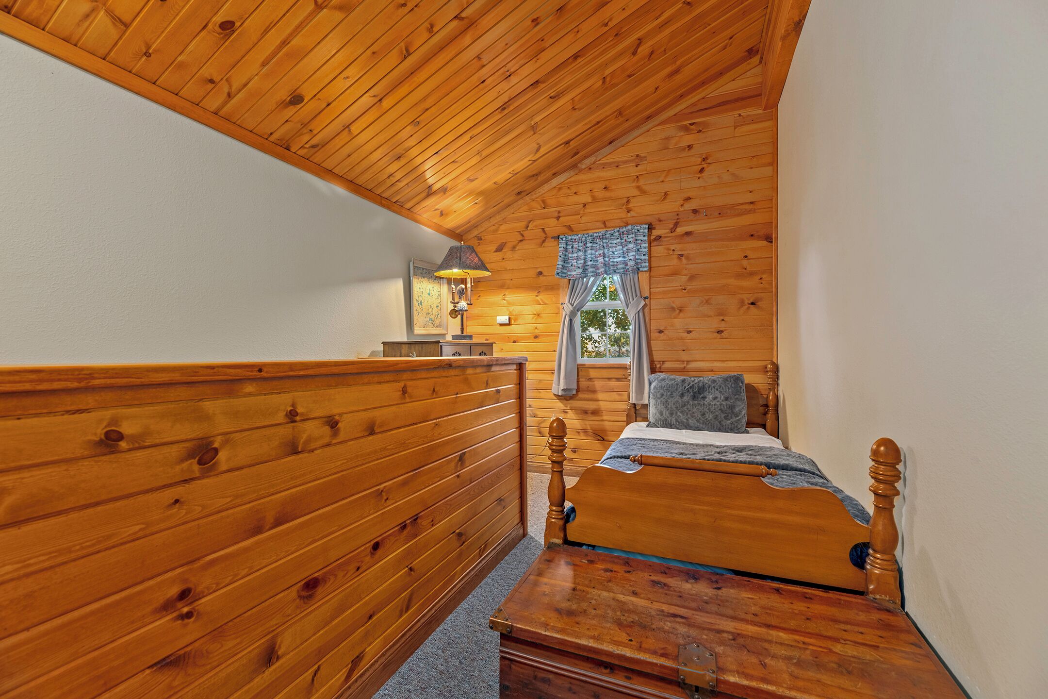 Une chambre dans une cabane en bois, avec un lit superposé, une petite table et une fenêtre avec des rideaux.