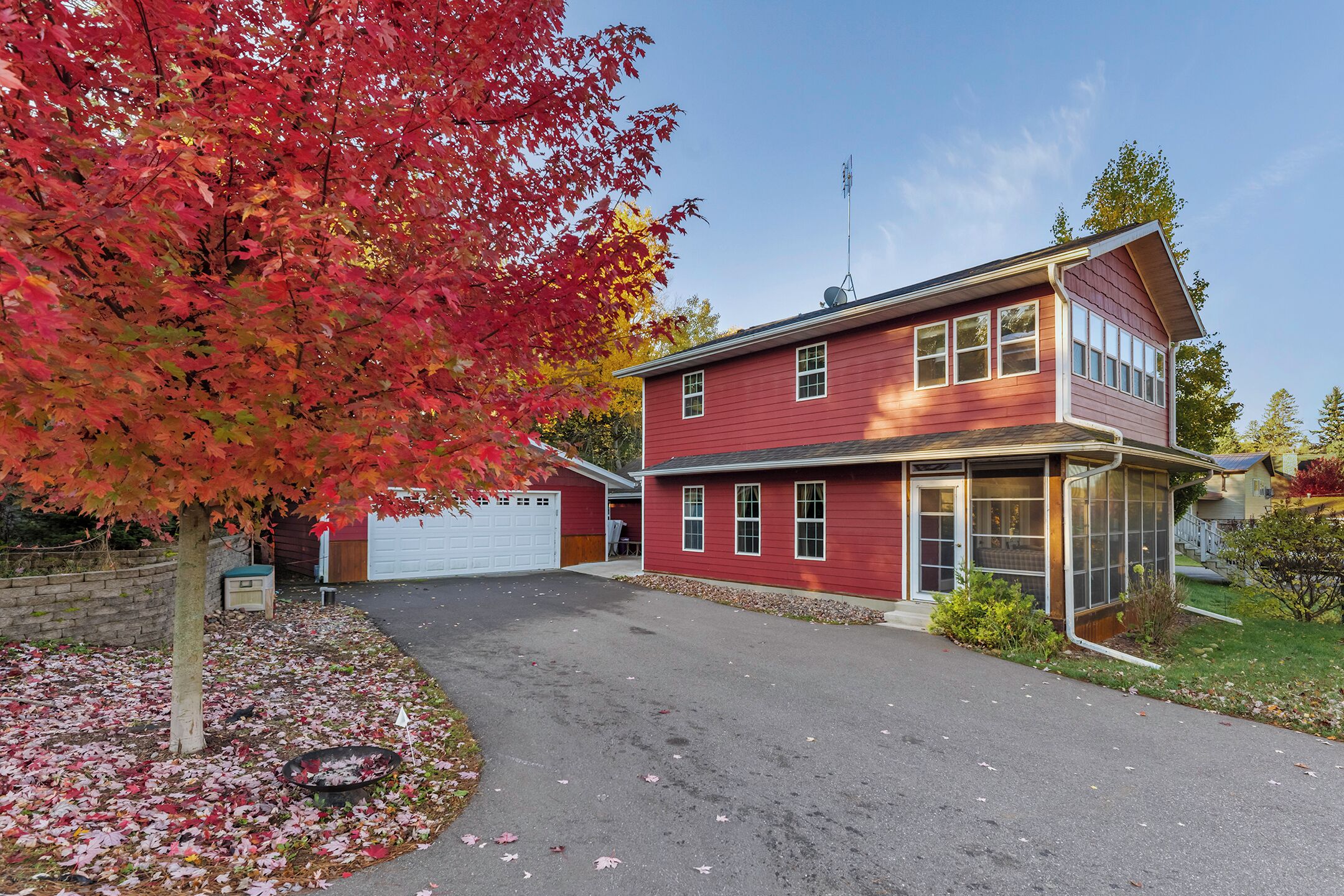 Une maison à deux étages avec un garage, une véranda et une allée.