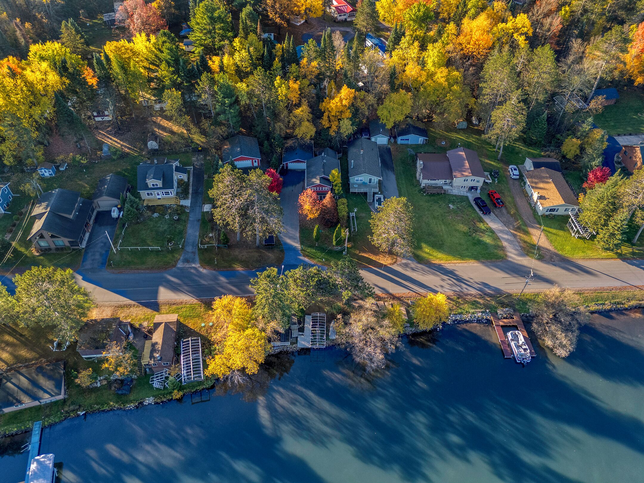 Une vue aérienne d’un quartier résidentiel avec des maisons, un quai et une étendue d’eau.