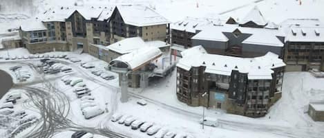 Estación de esquí cubierta de nieve con varios edificios, un estacionamiento y un telesilla.