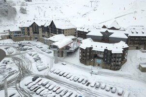 Estación de esquí cubierta de nieve con varios edificios, un estacionamiento y un telesilla.