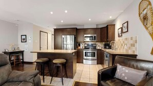 Una cocina moderna con armarios de madera oscura, electrodomésticos de acero inoxidable y una isla central con taburetes.