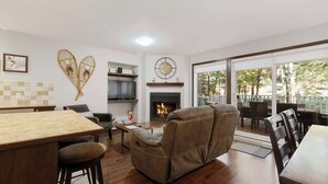 Una sala de estar con chimenea, comedor y vistas al exterior.