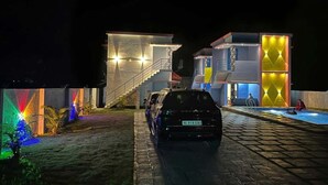 Un edificio moderno con una escalera que sube a un segundo piso, una piscina y un automóvil estacionado.