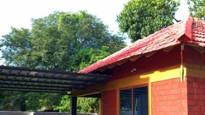 Una pequeña casa de ladrillo rojo con techo de tejas, una ventana y un porche cubierto.