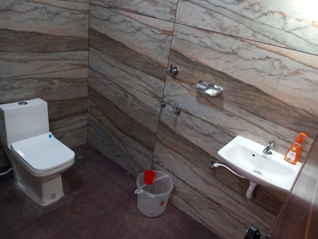 A bathroom with a toilet, sink, and marble walls.